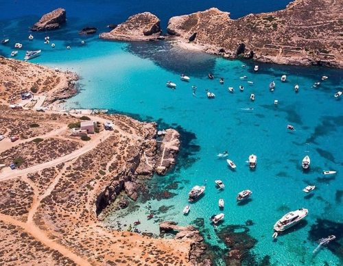 Aerial view of turquoise water and boats at the Blue Lagoon near Comino, Malta.