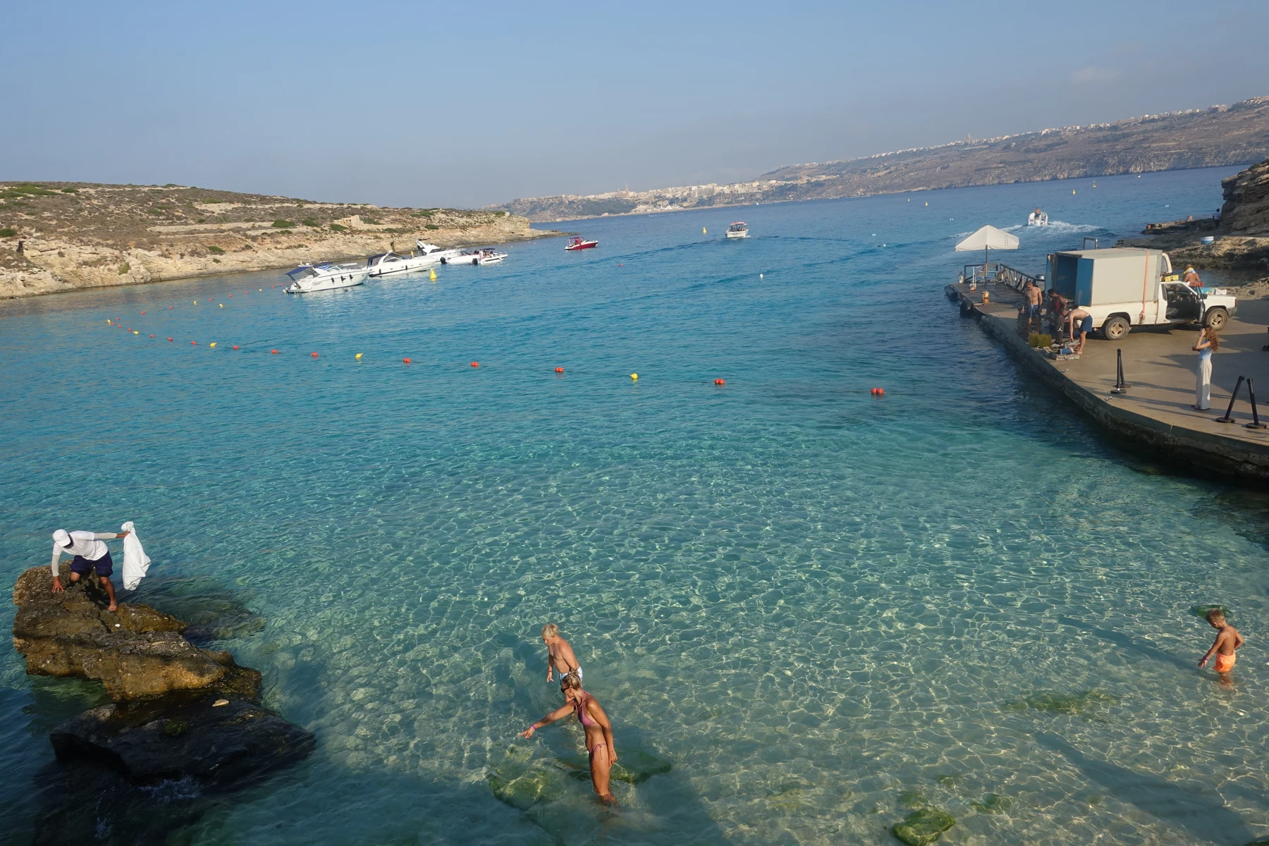 Holidaymakers swimming in the turquoise water of the Blue Lagoon on Comino, Malta.