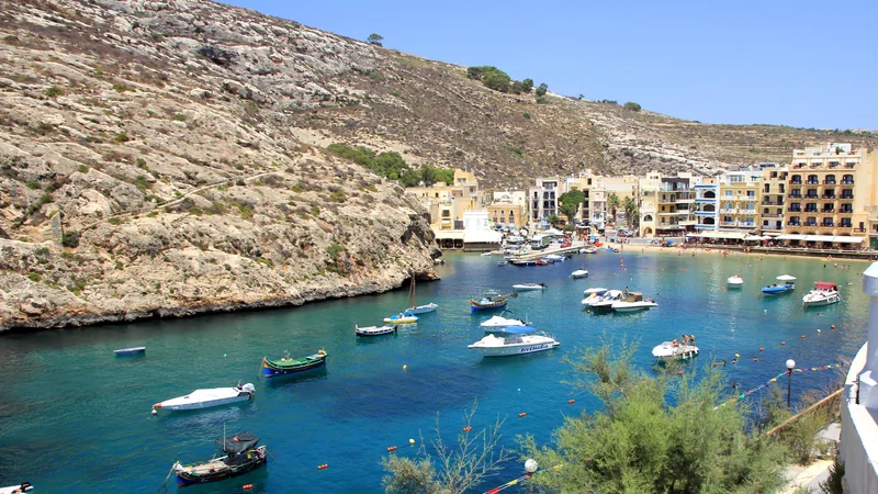 Small boats on the turquoise water of Xlendi Bay in Gozo.