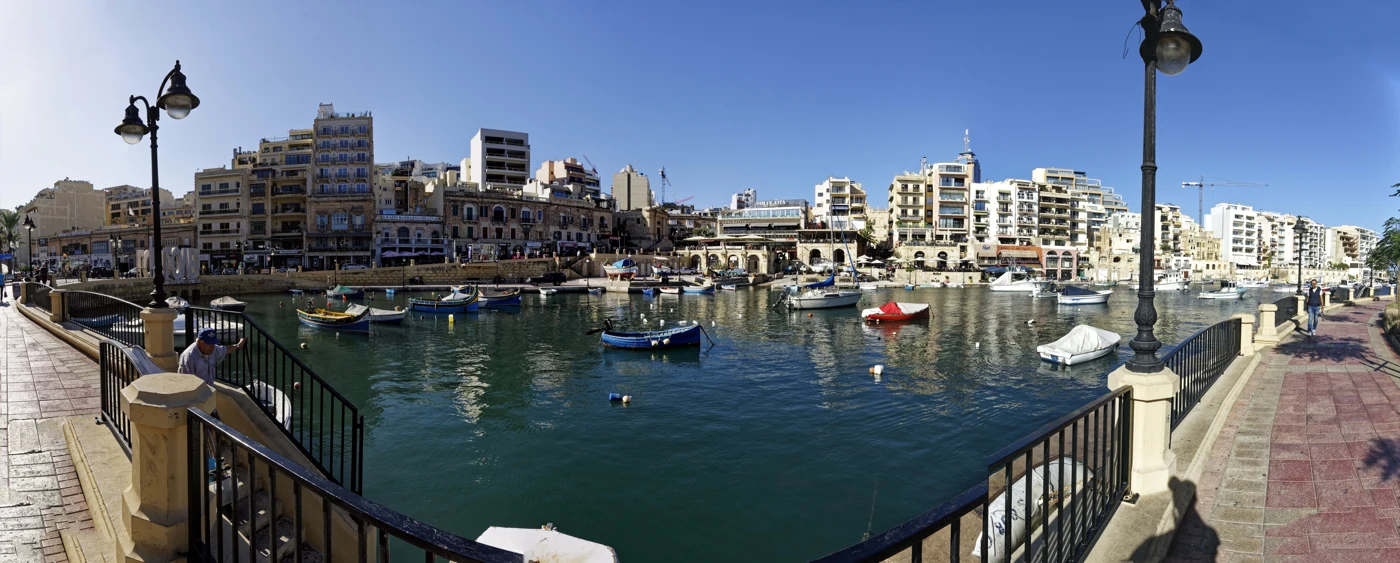 Boats and waterfront restaurants around Spinola Bay in St Julian’s, Malta.
